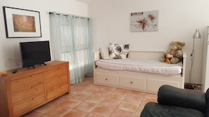 A bedroom with a bed, a dresser, a television, a teddy bear, and a lamp.