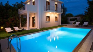 Una casa de dues plantes amb piscina, un balcó i gandules.