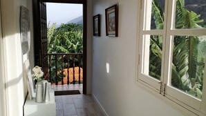 Ein Flur mit Blick auf einen Balkon, einer Metall-Kaffeekanne und gerahmten Bildern an der Wand.
