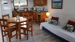 Eine kompakte Küche mit Holzausstattung, einem Esstisch mit Stühlen, einer Mikrowelle und einem Kühlschrank.