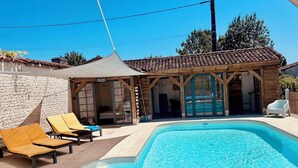 Une piscine dotée de chaises longues et d’un espace abrité avec des poutres en bois.