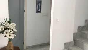 A hallway with a marble staircase, a wooden table with a vase of flowers, and a door with a decorative frame. - Penthouse With Sea And Mountain View And Communal Swimming Pool  (Nerja)