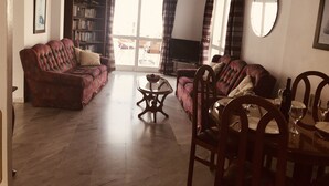 A living room with a sofa, a television, a dining table with chairs, and a bookshelf. - Penthouse With Sea And Mountain View And Communal Swimming Pool  (Nerja)