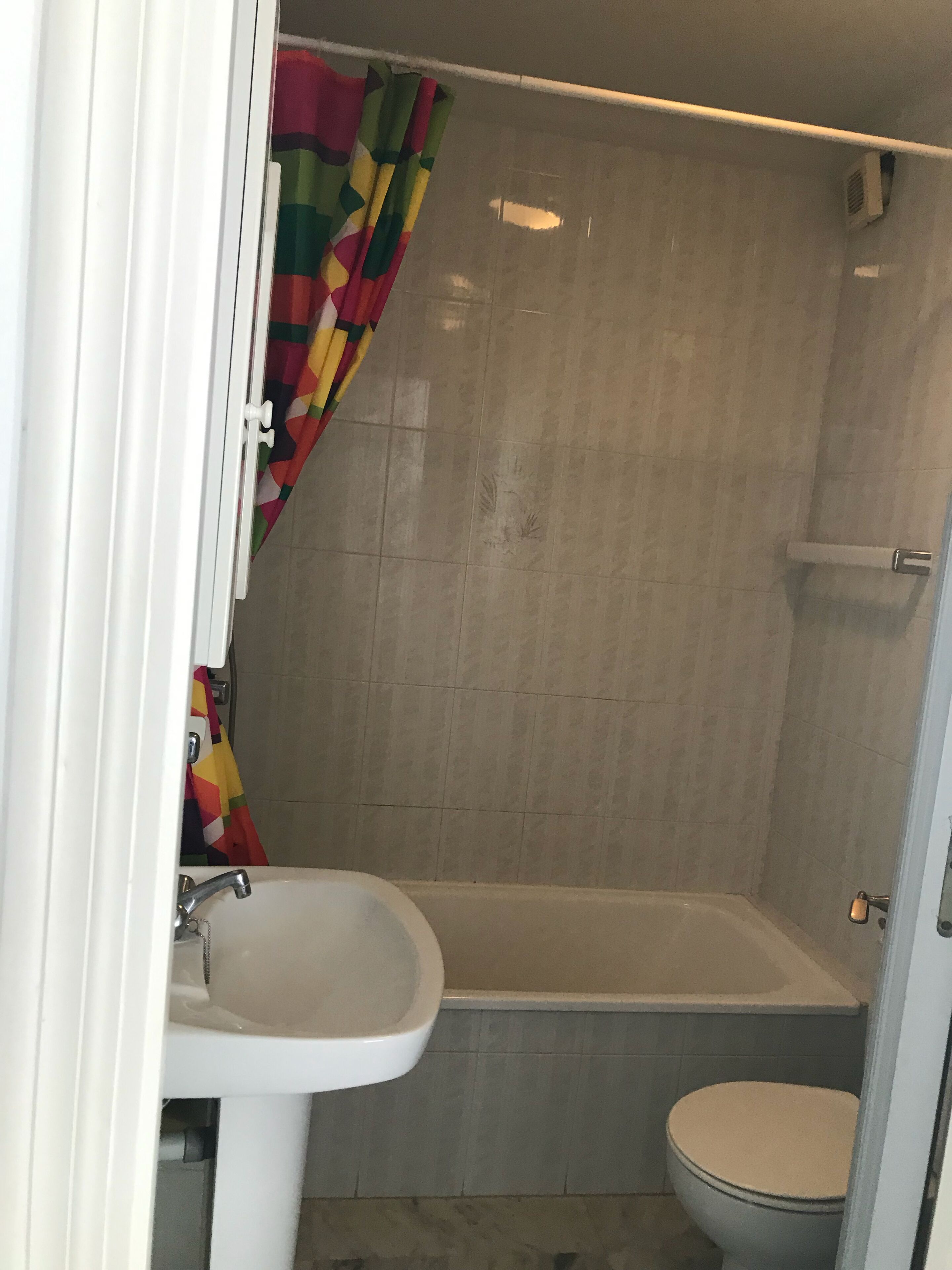 Een badkamer met bad, toilet en wastafel.