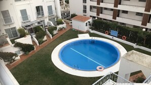 A residential building with a swimming pool, a small garden, and a staircase leading to the upper floors. - Penthouse With Sea And Mountain View And Communal Swimming Pool  (Nerja)