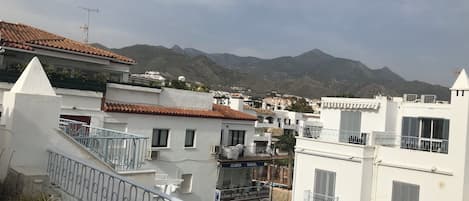Un quartier résidentiel caractérisé par des bâtiments blancs, des balcons et un paysage montagneux en arrière-plan.