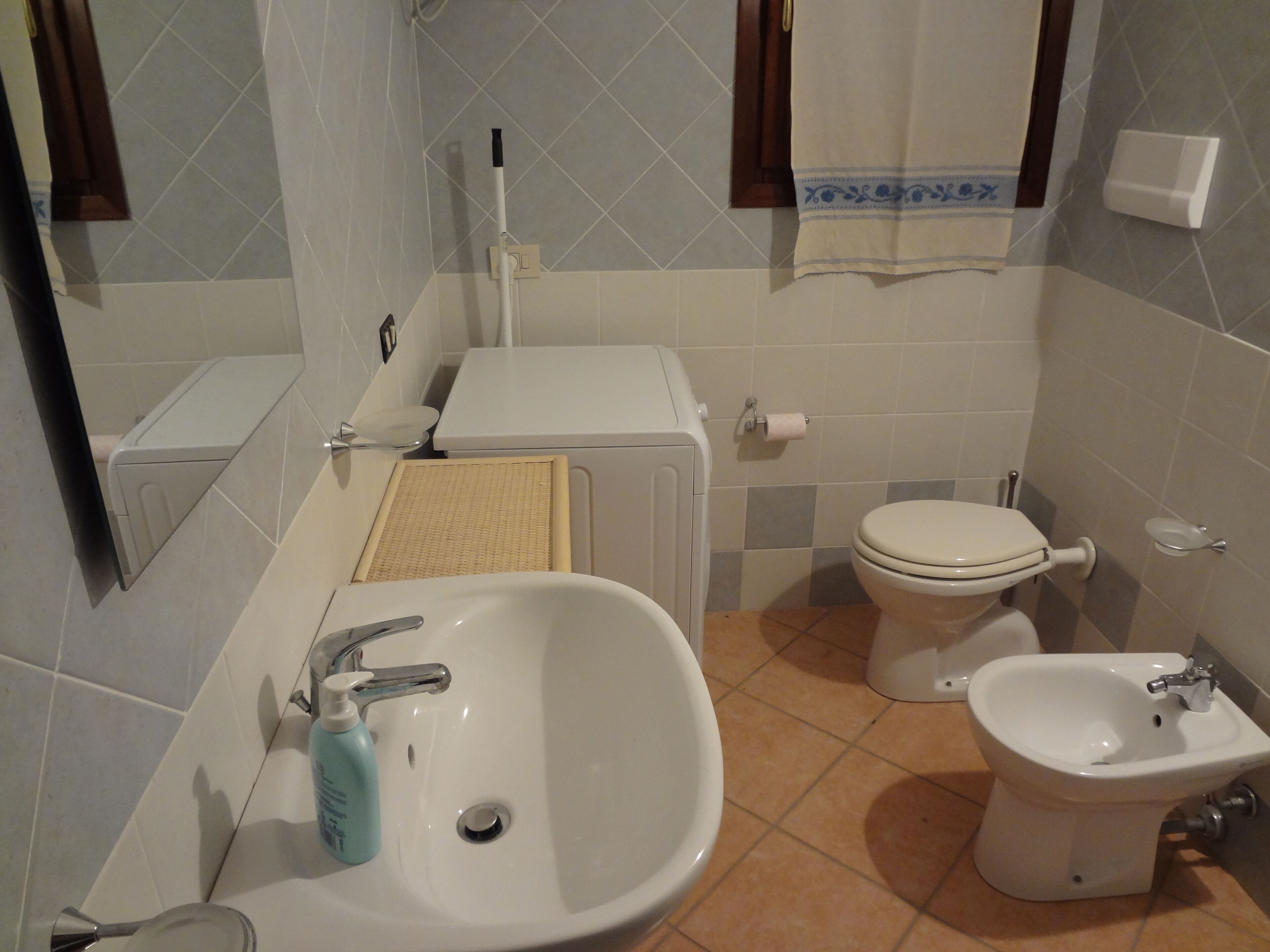 A bathroom with a sink, toilet, bidet, and a towel rack.