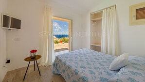 A bedroom with a bed, a TV, a small table with a vase of flowers, and a view of the sea. - Villa Josephine with pool in Costa Paradiso (Costa Paradiso)