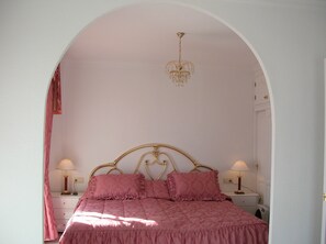 A bedroom with a bed, two bedside tables, a chandelier, and an arched doorway. - Beautiful villa, panoramic views of sea and mountains, close to town (almunecar,)