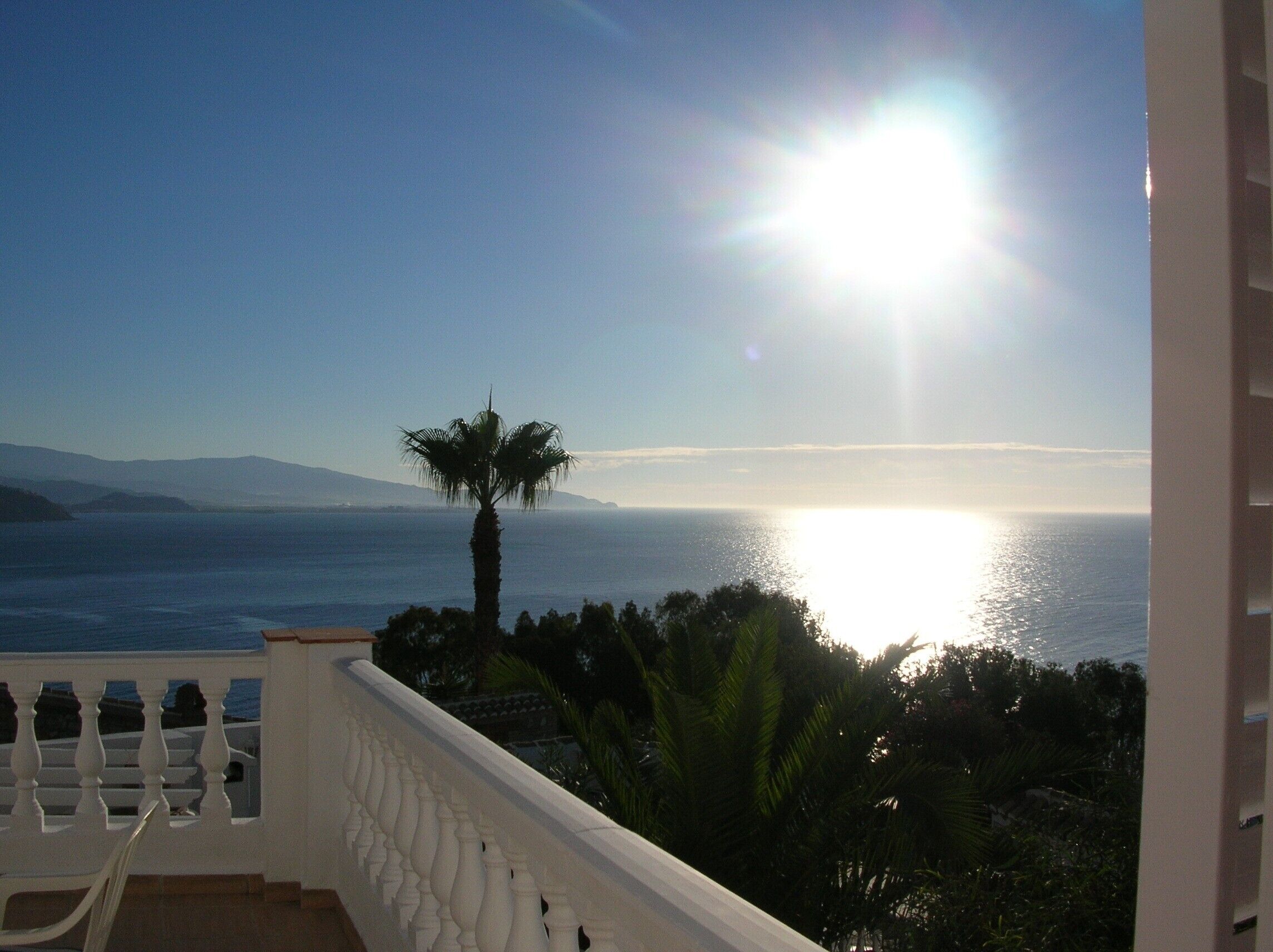 A balcony with a view of the sea and mountains.