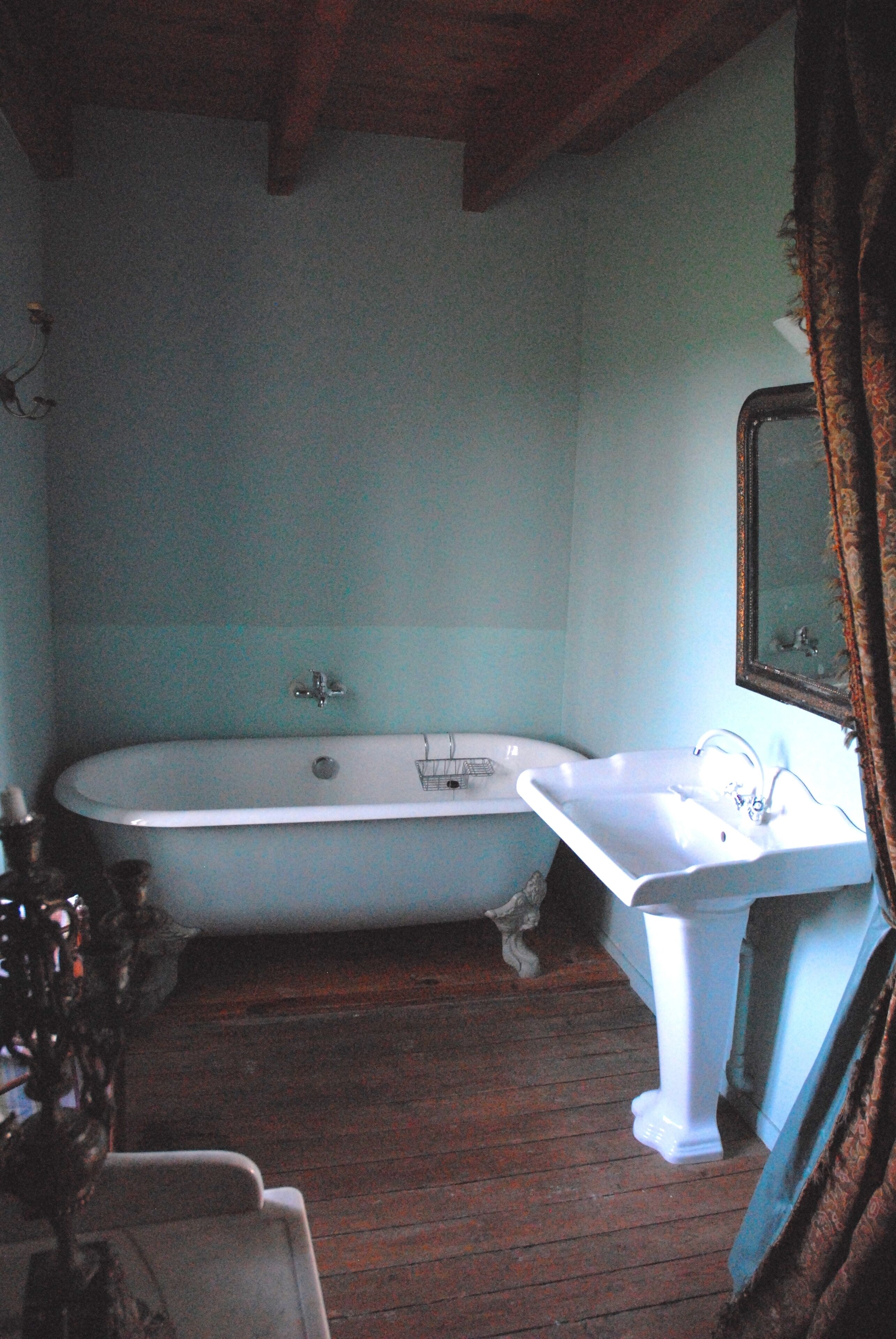 Une salle de bain avec une baignoire, un lavabo et un plancher en bois.