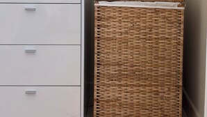 Ein weißes Hängezimmmer mit Schubladen, ein gewebter Korb und ein gerahmtes Bild an der Wand.