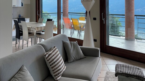 Ein modernes Wohnzimmer mit einer Couch, einem Essbereich mit Stühlen und einem Balkon mit Meerblick.