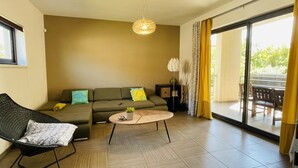 A modern living room with a sofa, a coffee table, and a chair. There is a large window with curtains and a view of the outdoors. - House Zara Medulin - Beautiful modern house (Medulin)