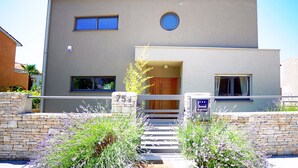 A modern two-story building with a stone facade, a circular window, and a small entrance. - House Zara Medulin - Beautiful modern house (Medulin)
