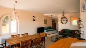 Een woonkamer met een bank, een eettafel met stoelen en een televisie.