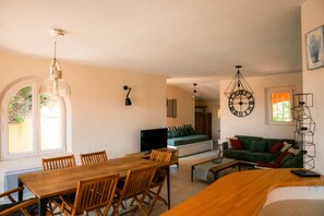 A living room with a sofa, a dining table with chairs, and a TV.