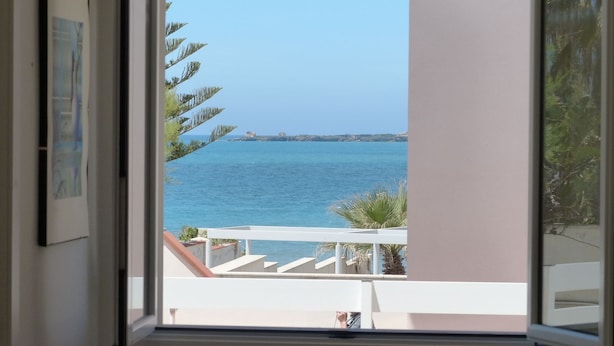 Un balcón con vista al mar y una costa lejana.
