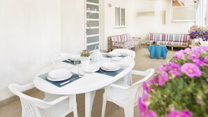 Un comedor blanco con una mesa redonda, sillas blancas y un sofá a rayas.