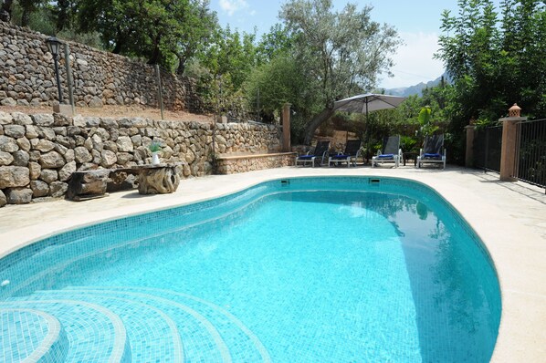 A swimming pool with a stone wall and lounge chairs. - Beautiful views of Sóller, private pool and BBQ, 3 kms to Sóller (Sóller)