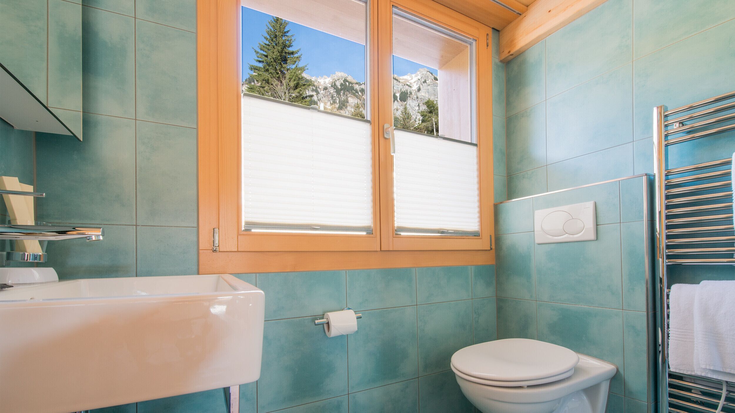 A bathroom with a window, a sink, and a toilet.