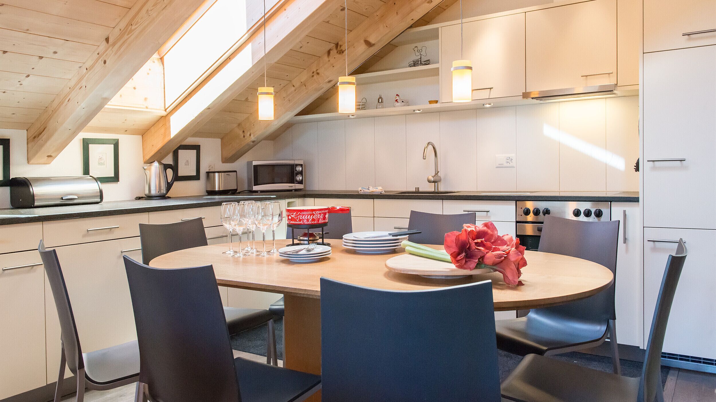 A modern kitchen with white cabinets, a dining table set with plates, glasses, and a centerpiece.