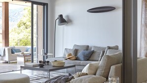 Ein modernes Wohnzimmer mit einer Couch, einem Couchtisch und Blick ins Freie.
