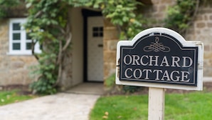 A sign for Orchard Cottage with a stone building in the background. - Orchard Cottage - sleeps 8 guests  in 4 bedrooms (Ilminster)