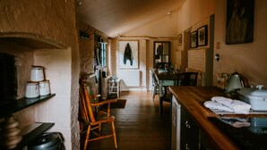 A narrow kitchen with wooden floors, a wooden chair, a table with a kettle, and a radiator. - Apple Cottage - A stylish country retreat, it's the ideal getaway. (Wimborne)