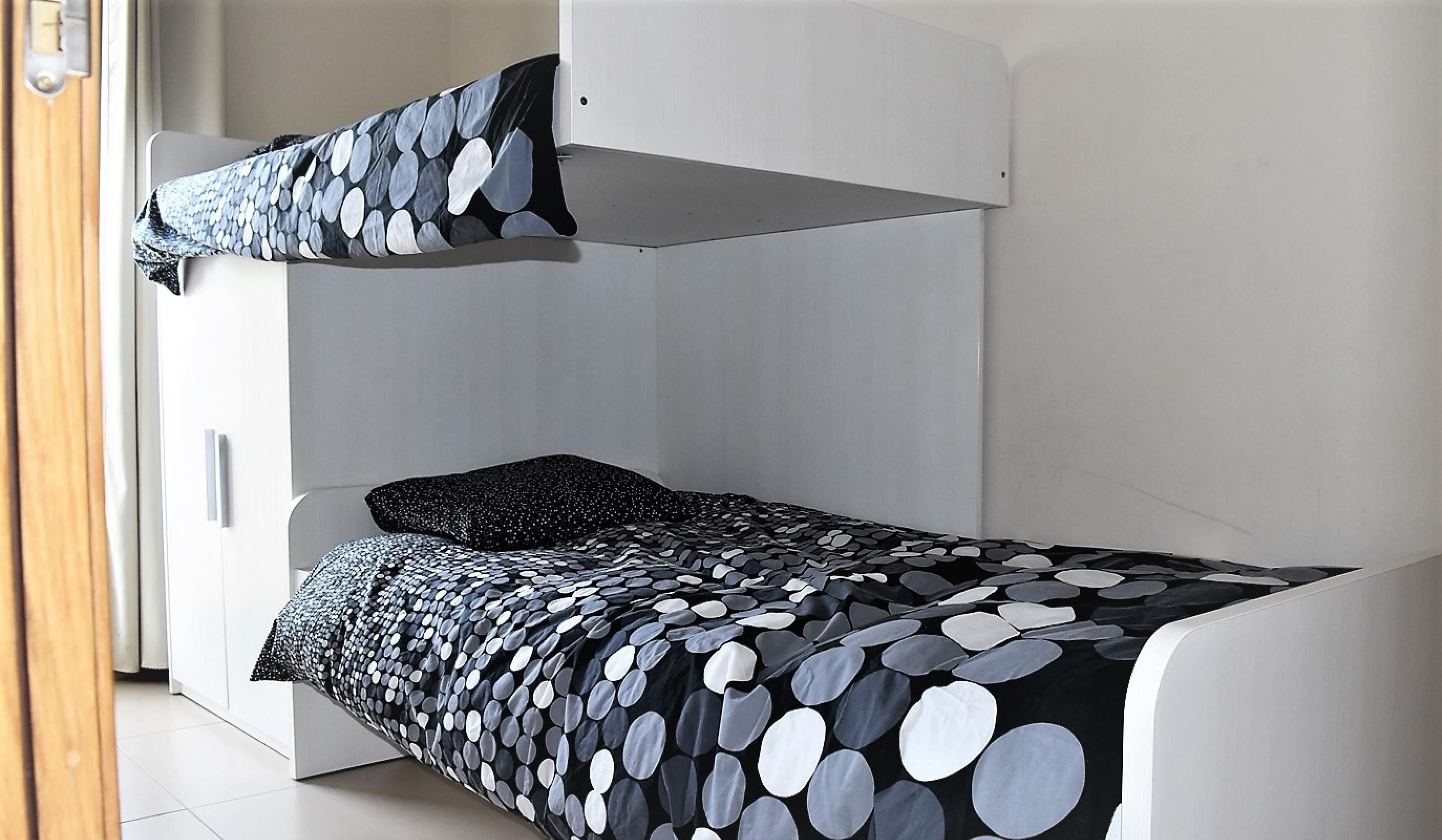 Ein Stockbett mit einer Betttdecke mit Punkten und einem Kopfkissen.