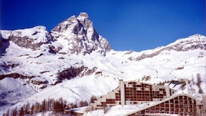 A mountain lodge with a prominent peak in the background, surrounded by snow-covered terrain. - Autonomous snow outing, 5 beds! <br>Private exit to the snow, 5 beds! (Breuil-Cervinia)