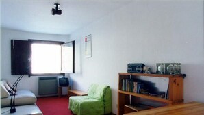A living room with a red carpet, a green chair, a wooden table, a bookshelf, and a television. - Autonomous snow outing, 5 beds! <br>Private exit to the snow, 5 beds! (Breuil-Cervinia)