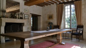 Una habitación amplia con una gran mesa de madera, una chimenea y un ventanal con cortinas.
