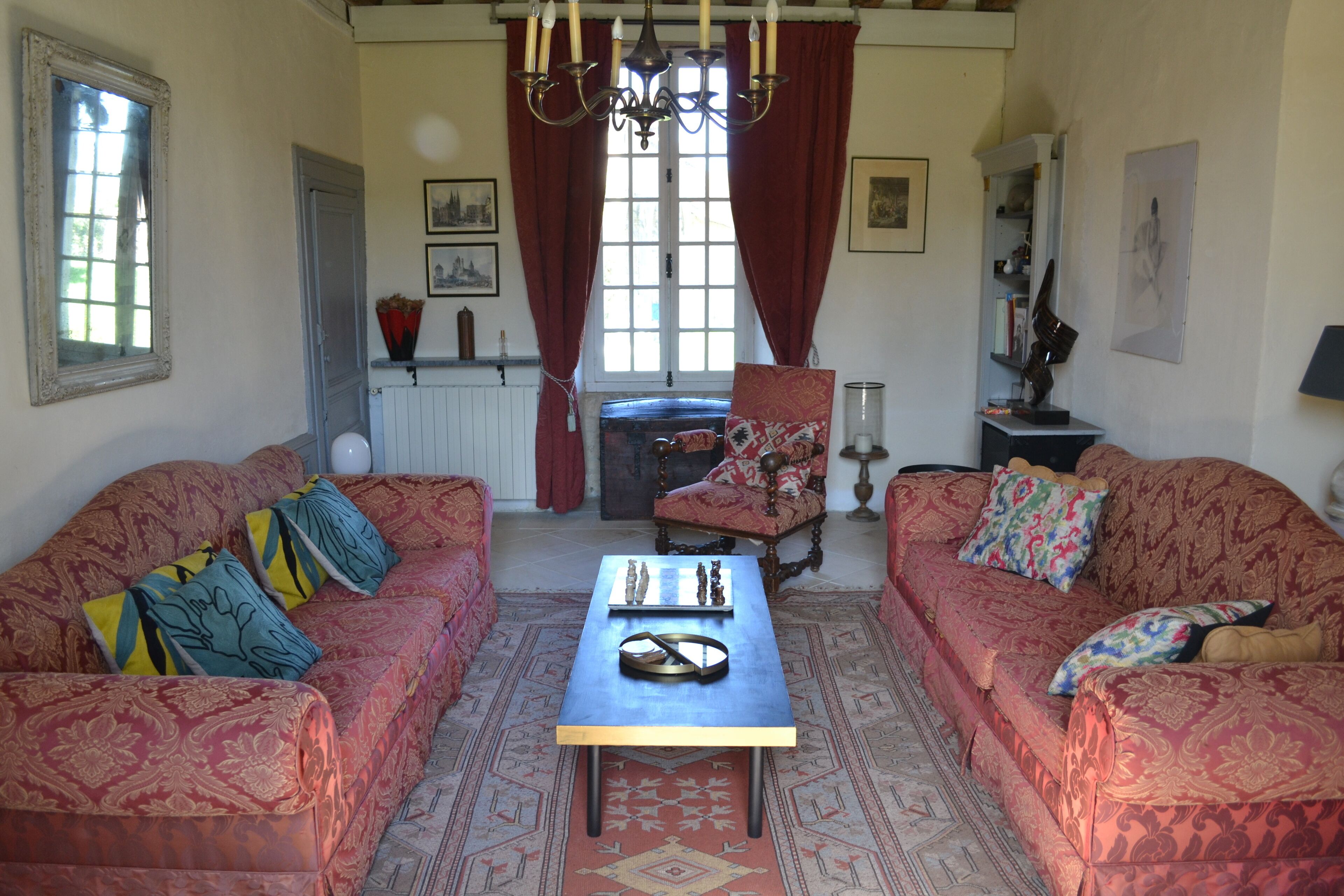 A room with two patterned sofas, a wooden coffee table, and a chandelier.