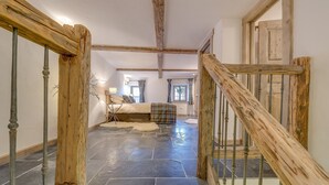 Un escalier avec des rampes en bois menant à une chambre à coucher qui contient un lit, une fenêtre et une porte.