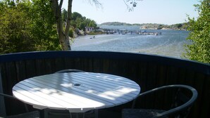 Un tavolo rotondo con sedie su un balcone affacciato su una distesa d'acqua con barche e pontili.