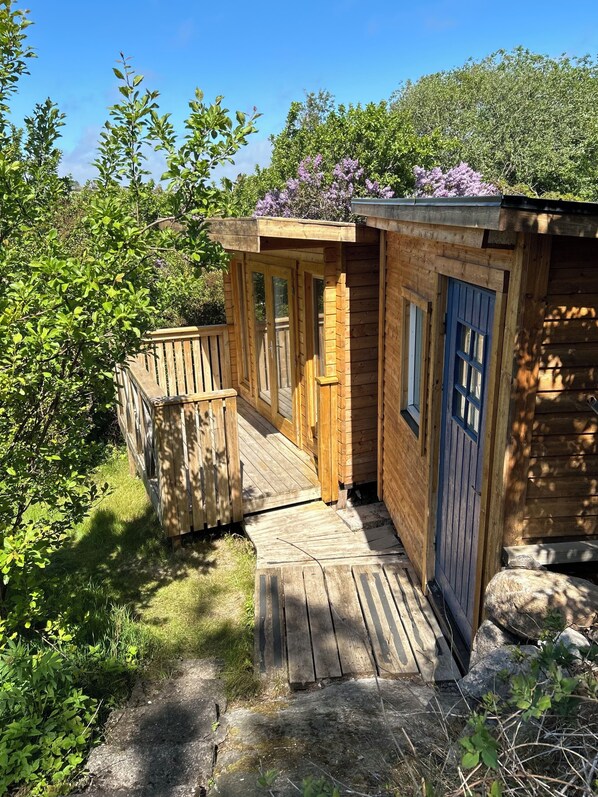 A wooden cabin with a porch, a door, and a window.