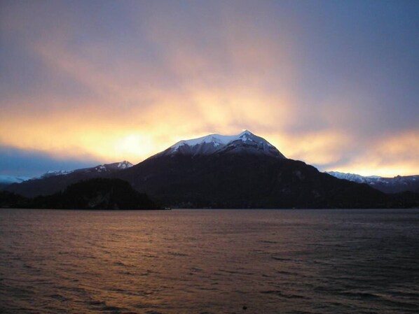 A mountain with snow-capped peaks and a body of water in the foreground. - Apartment with balcony, direct beach access (Varenna)