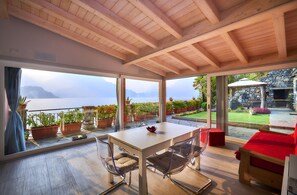 A modern room with a wooden ceiling, large windows, a table, and chairs. - Apartment with balcony, direct beach access (Varenna)
