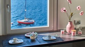 A kitchen with a view of a lake and mountains, a dining table with plates and a vase of flowers. - Apartment with balcony, direct beach access (Varenna)