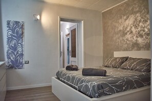 A bedroom with a bed, a wall-mounted light, a door, and a decorative panel. - Apartment with balcony, direct beach access (Varenna)