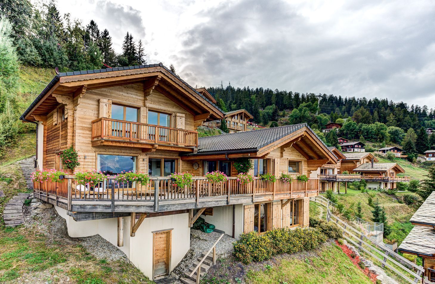 A wooden chalet with a balcony, surrounded by a mountainous landscape.