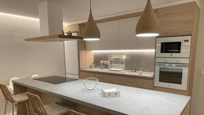 A modern kitchen with a central island, bar stools, pendant lighting, and built-in appliances. - Casa Rosita, free Wifi, 75 meters from the Niu Blau beach, ideal families. (Santa Eulalia del Rio)