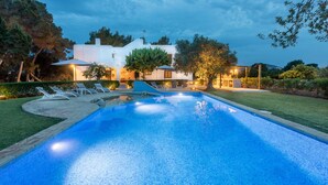 A swimming pool with lounge chairs and a well-lit house in the background. - Casa Rosita, free Wifi, 75 meters from the Niu Blau beach, ideal families. (Santa Eulalia del Rio)