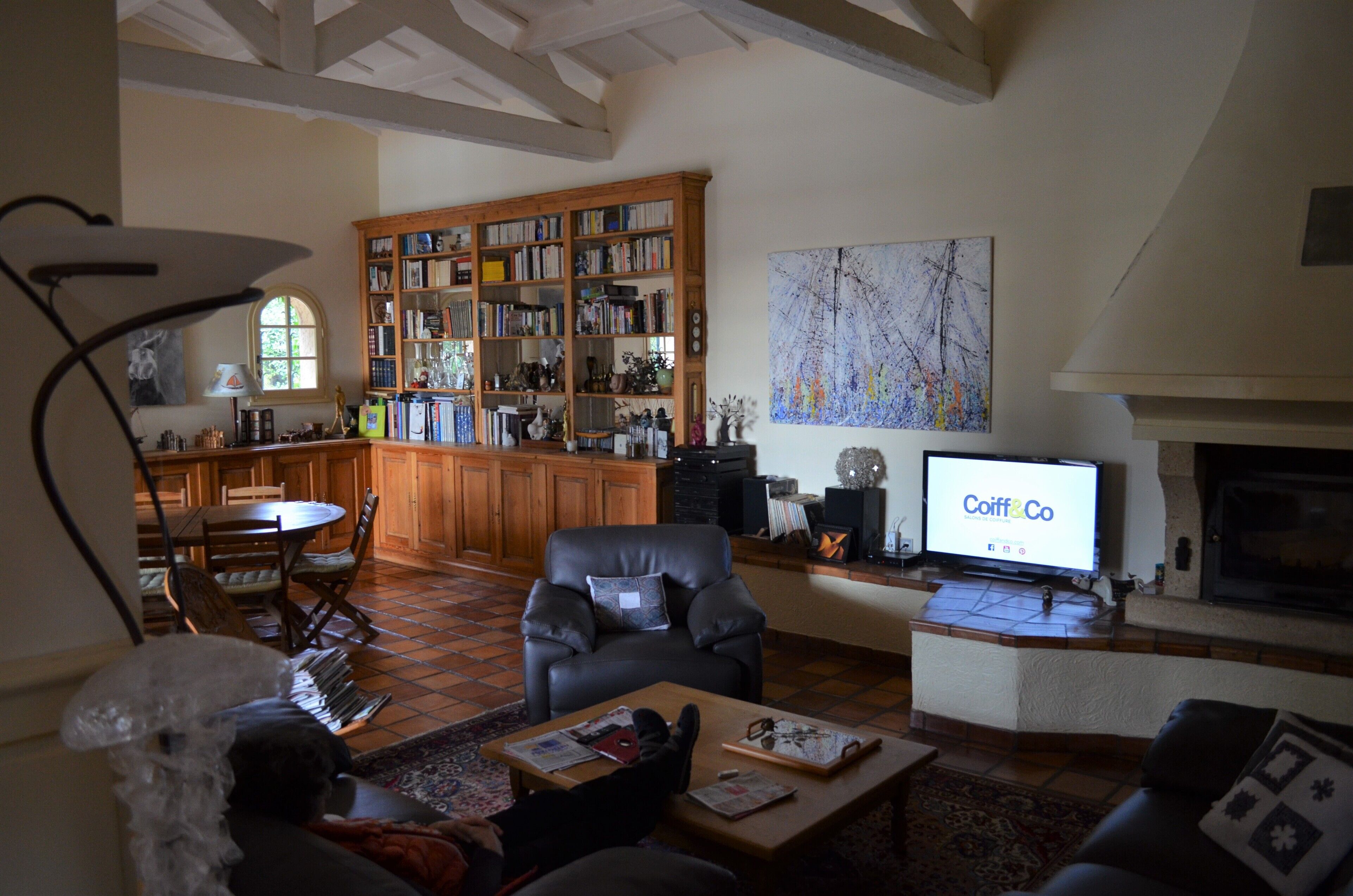 A living room with a fireplace, a television, a bookshelf, and a dining area with a table and chairs.