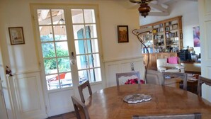 Un coin repas avec une table et des chaises en bois, une bibliothèque et une porte donnant sur un espace extérieur.