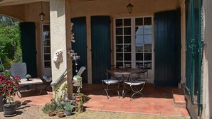 Une terrasse extérieure avec une table et des chaises, des plantes en pot et une statue.