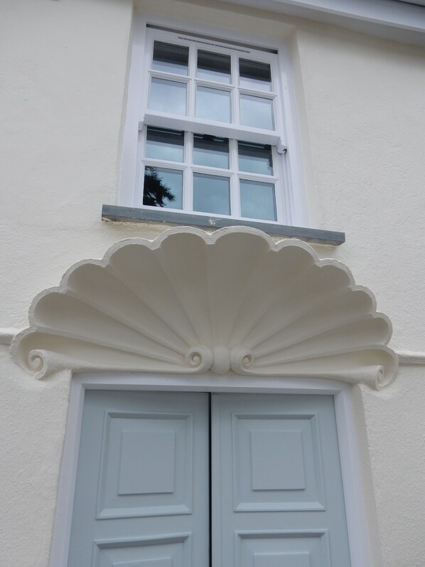 A building with a white facade, a window with six panes, and a decorative white arch above a set of double doors. - Cottage (2 bedrooms - 3 beds) Polruan Fowey-stunning views over the estuary+sea (Polruan)