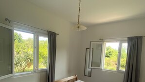 A bedroom with a bed, a window, a mirror, and a ceiling light. - Villa in Gosici, Radovici. Private Pool, BBQ, peaceful location, stunning views. (Gošići)