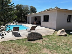 Ein Pool mit Liegestühlen, eine Terrasse und ein Gebäude mit einem Ziegeldach.
